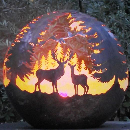 Stahlkugel in der Dämmerung mit Hirsch und Hirschkuh vor einem Tannenwald